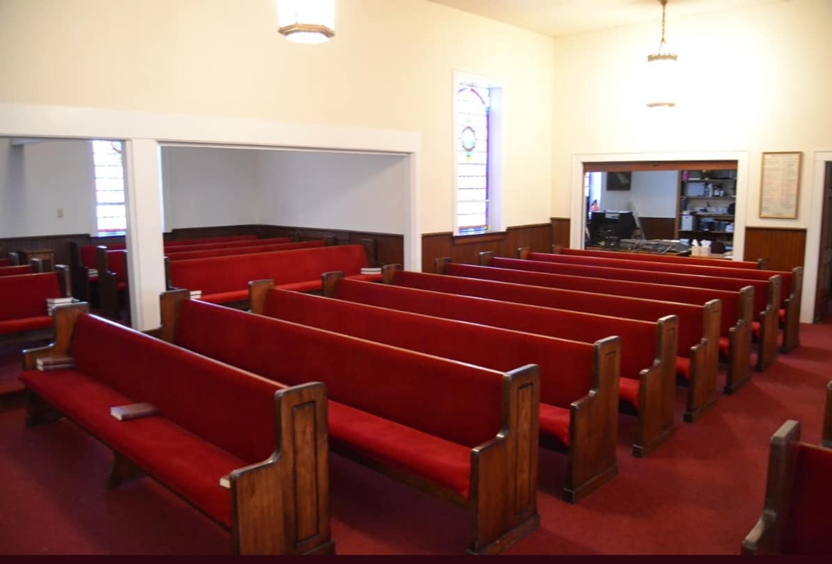 Sanctuary Interior – Rear View (Before Renovation, 2013) Pre-renovation view of Rawls Baptist Church sanctuary with red pews, wooden wainscoting, and visible media equipment at the rear wall.