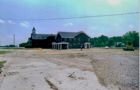 Nearly Finished, 2005 Exterior of Rawls Baptist Church in 2005 nearing completion after major expansion, showing new fellowship hall addition, finished brickwork, and open parking area under bright summer sky.