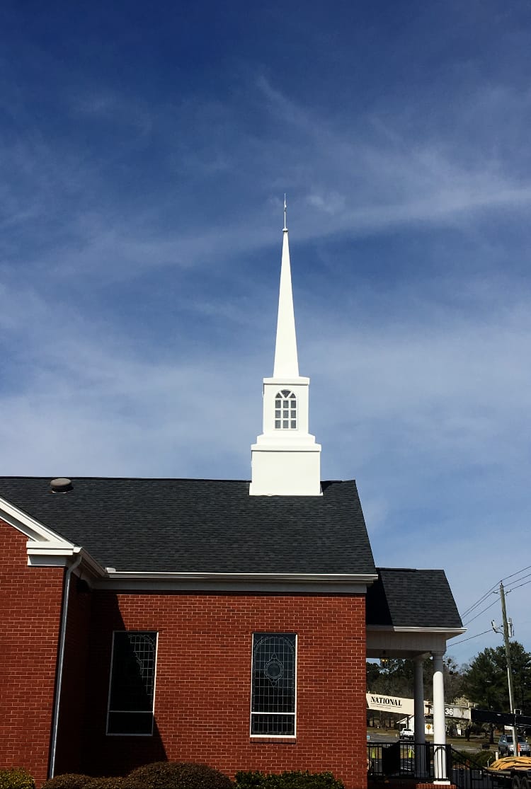Completed Steeple Installation (2018) Completed steeple at Rawls Baptist Church after 2018 restoration, featuring bright white structure above red brick sanctuary.