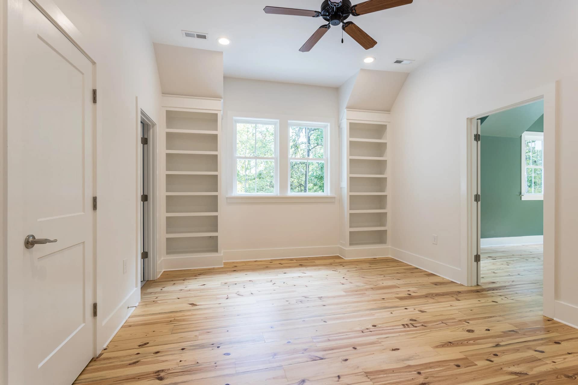 Bedroom with built-in shelving and hardwood floors in Pittsboro custom home