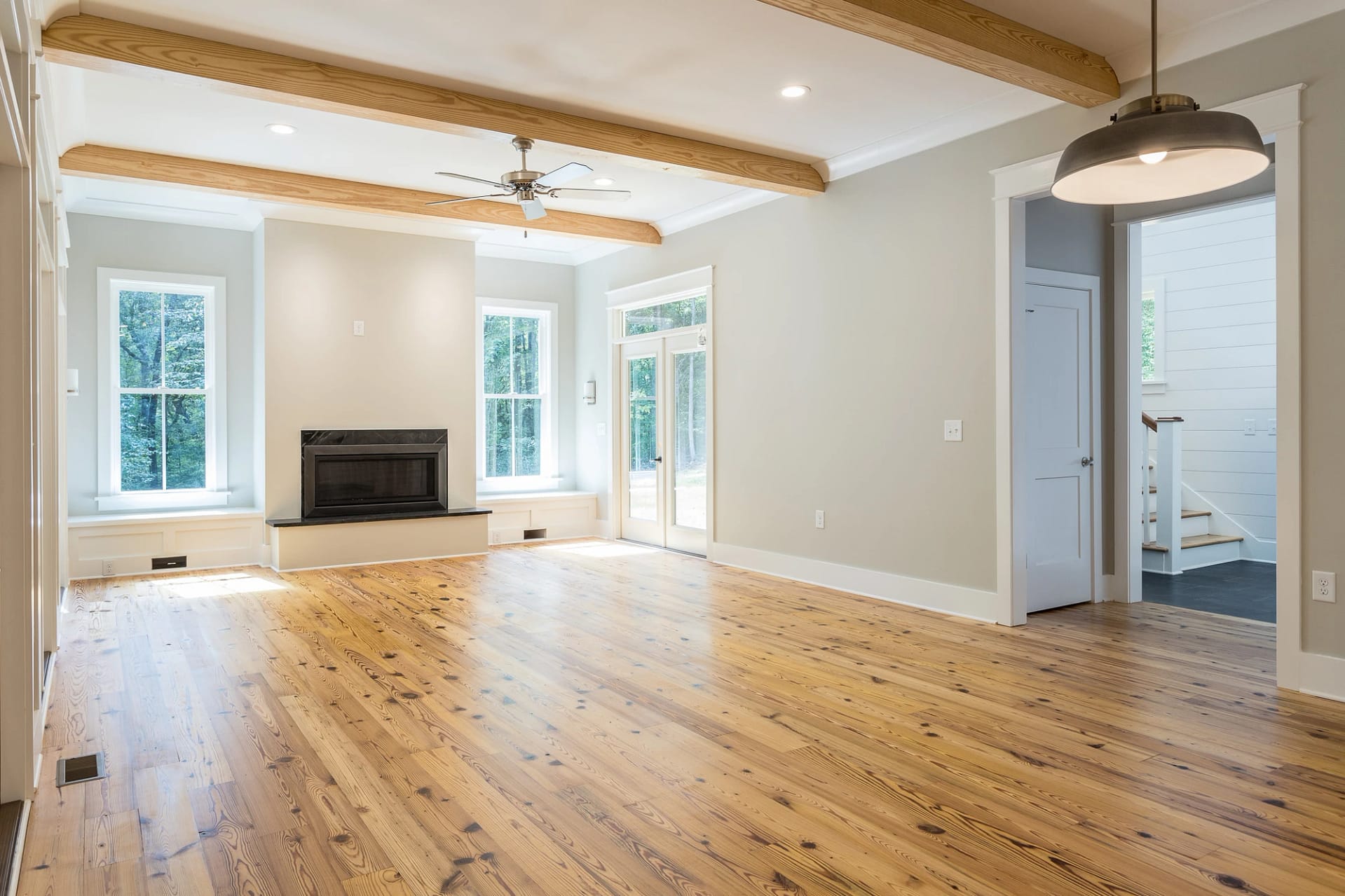 Living room with fireplace, exposed ceiling beams, and natural light in Pittsboro home