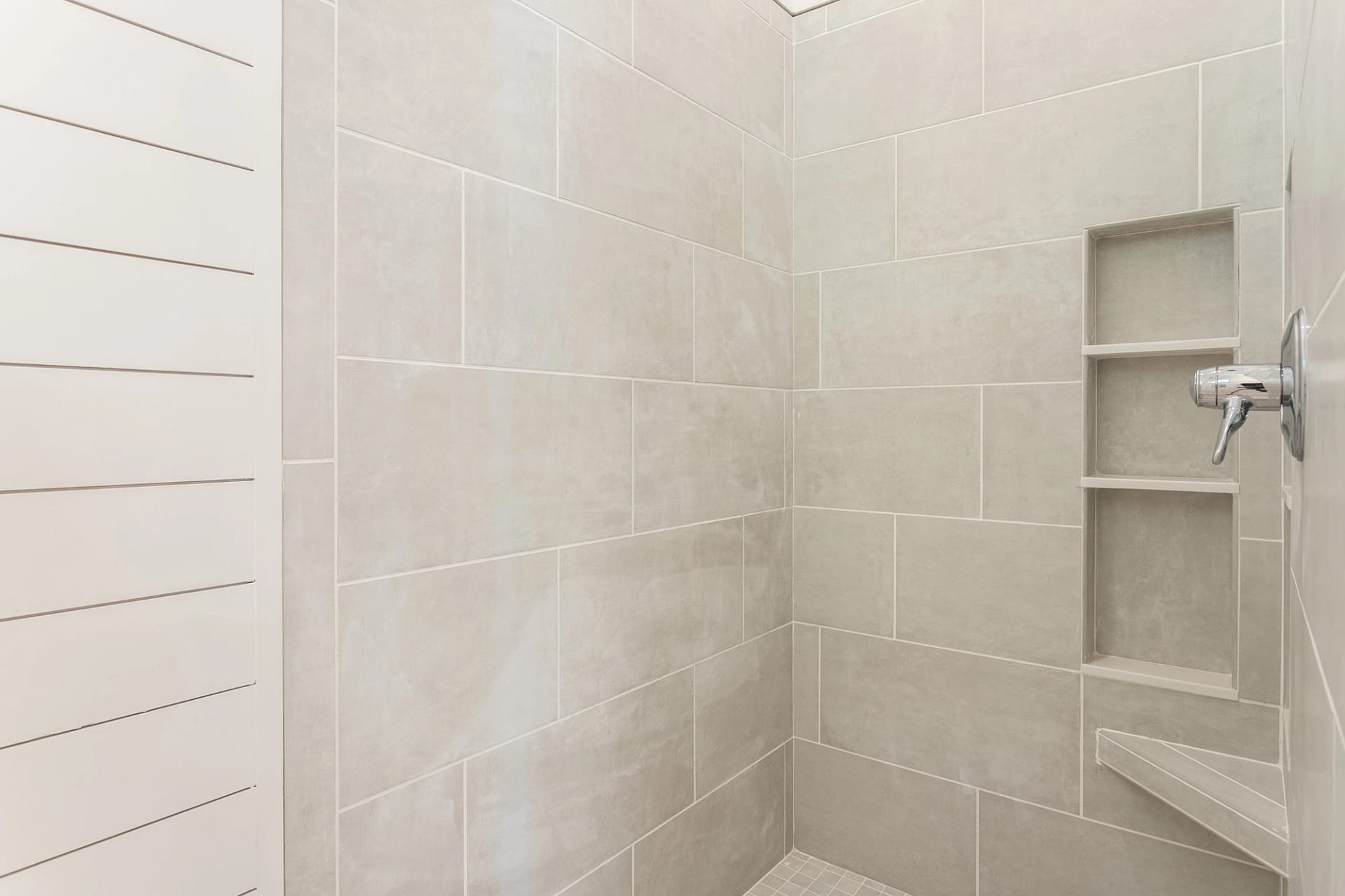 Walk-in shower with light tile and built-in niche in Pittsboro custom home