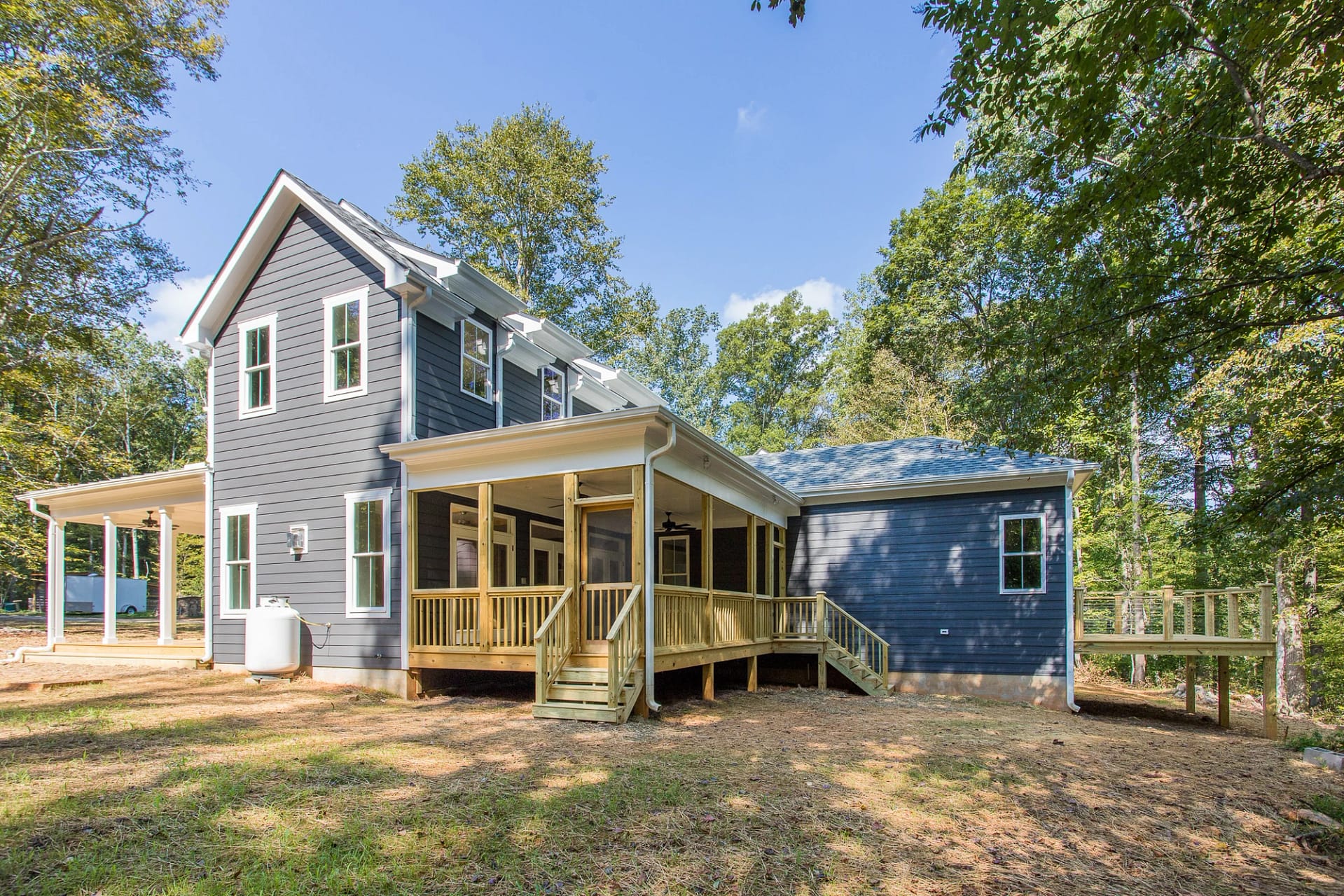 Rear exterior view of Pittsboro custom home with wraparound porch and natural setting