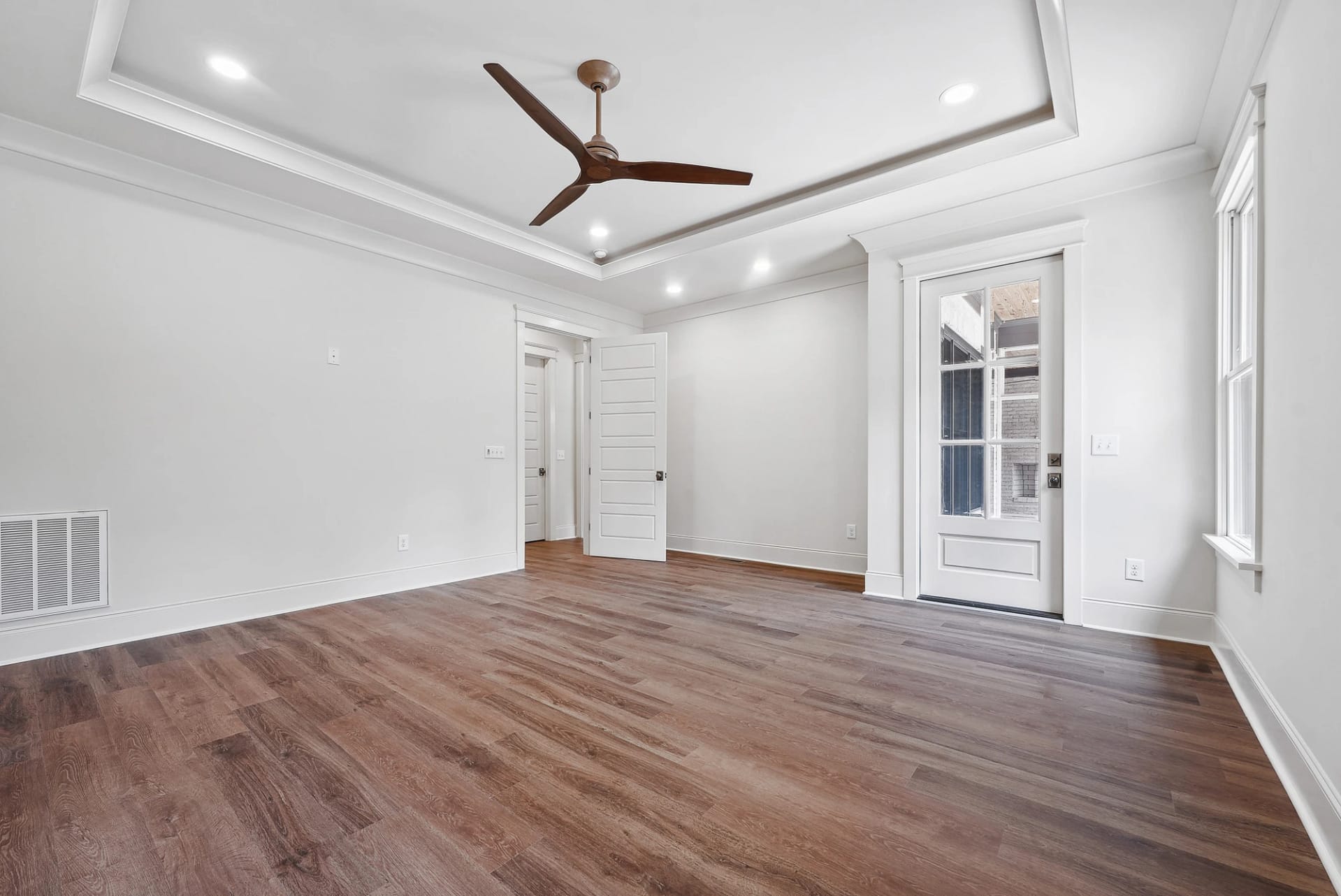Master bedroom with hardwood floors and tray ceiling in Holly Springs home