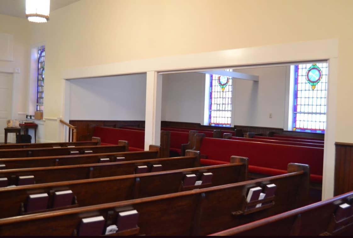 Sanctuary Interior – Side View Toward Front (Before Renovation, 2013) Left-side view of Rawls Baptist Church sanctuary prior to remodeling, with stained glass windows and red pews under soft pendant lighting.