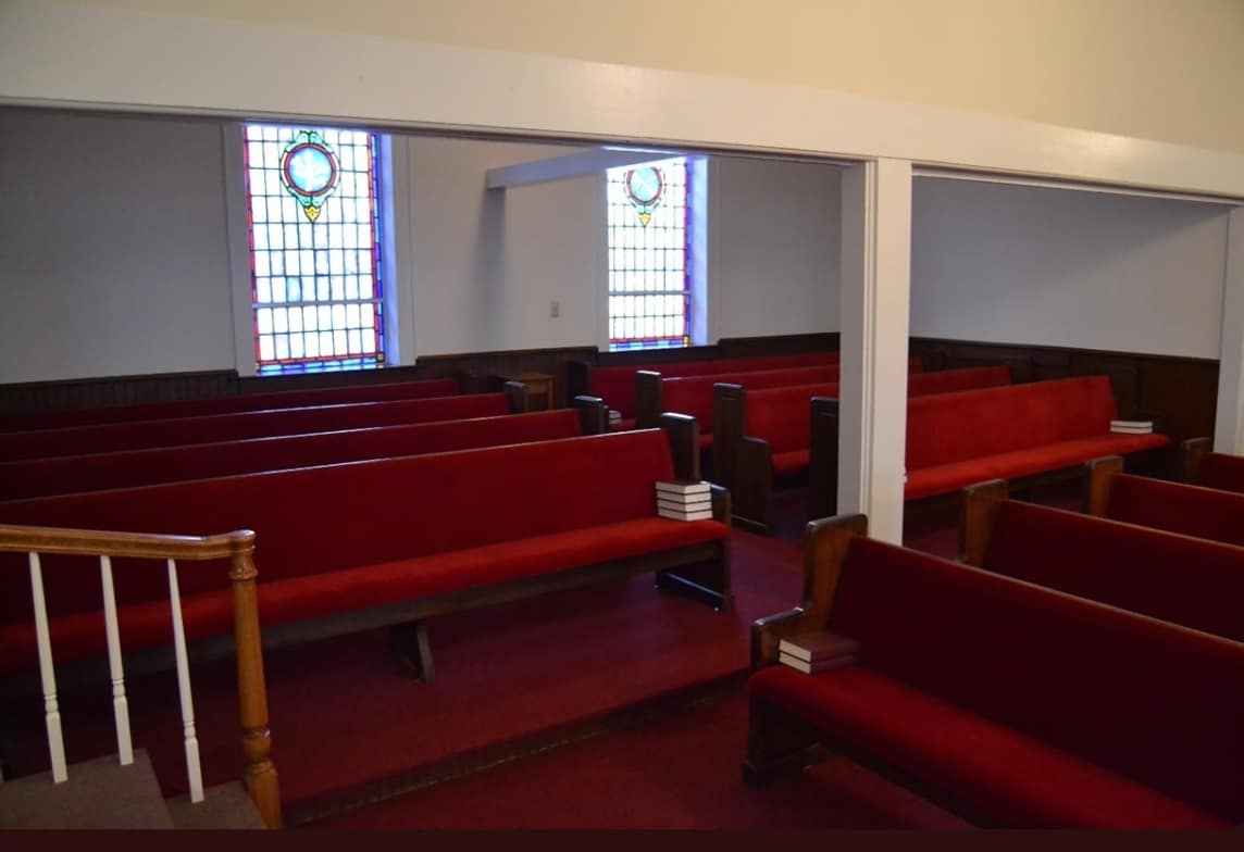 Sanctuary Interior – Center Seating Area (Before Renovation, 2013) Sanctuary seating before renovation at Rawls Baptist Church, highlighting red pews, stained glass details, and interior wall structure.