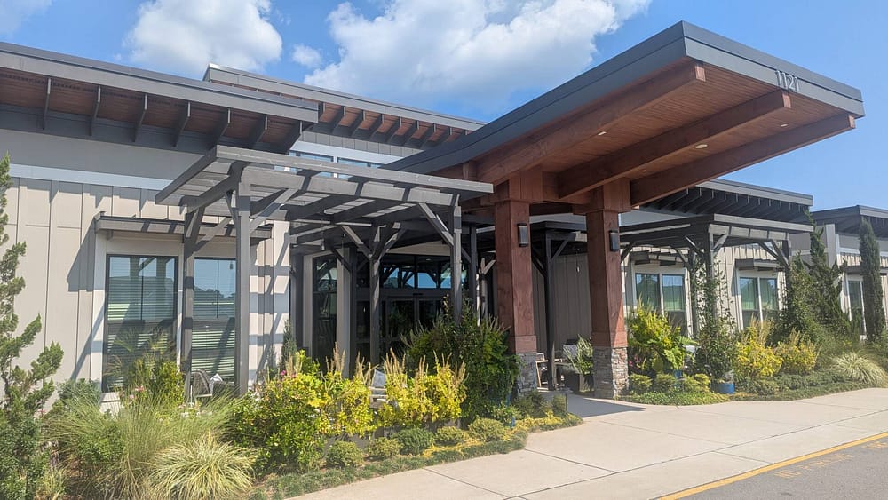 Calyx Senior Living Exterior Entrance with lots of greenery and clouds on a beauitful day