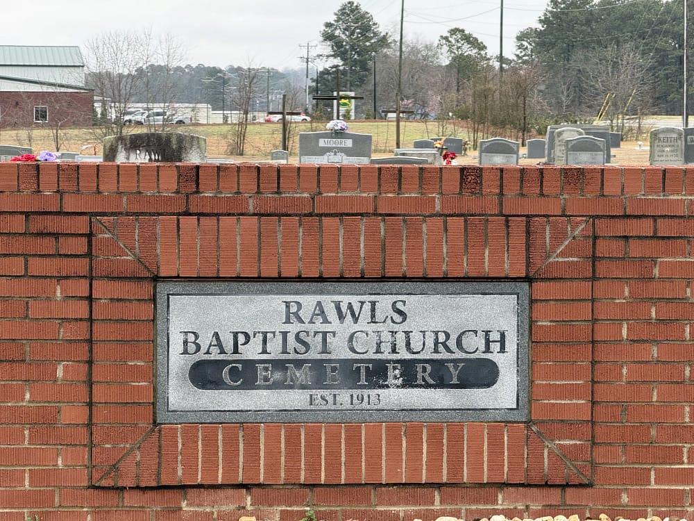 Rawls Baptist Church Cemetary sign made of brick with gravestones and 3 crosses in background