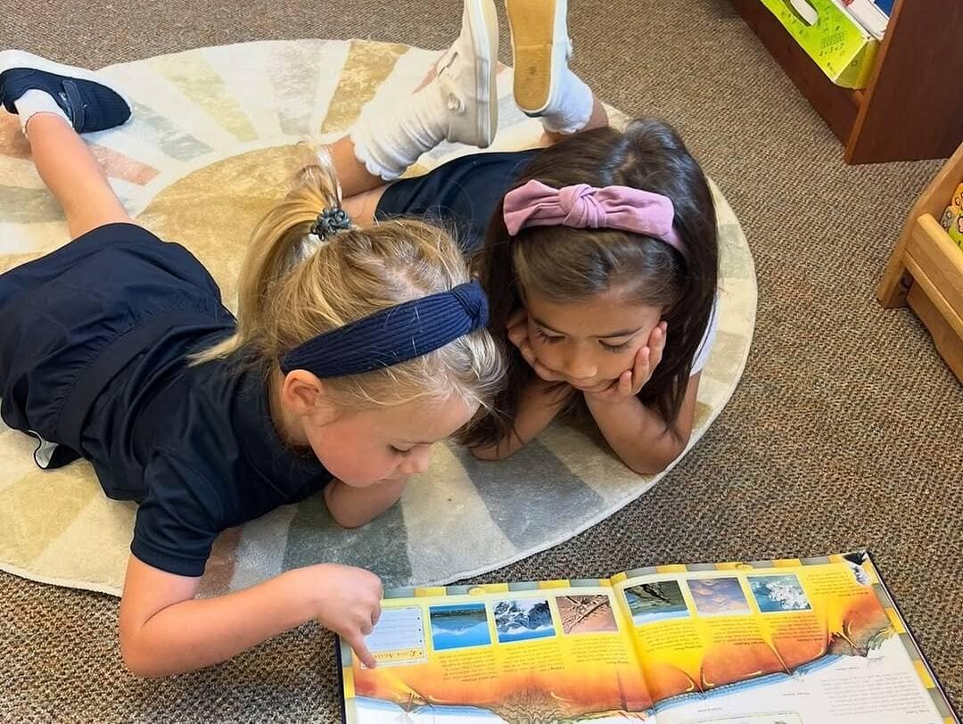 velos_girls_reading Velos Classroom with two girls reading a book on the floor