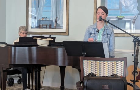 calyx_new02 Susanna and mother singing hymns and playing piano with a wall and pictures in the background