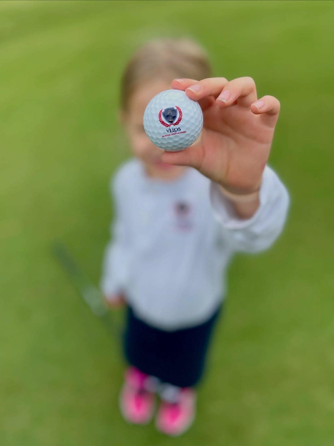 velos_golf_ball Child holding up a Velos Classical Christian School branded golfball.