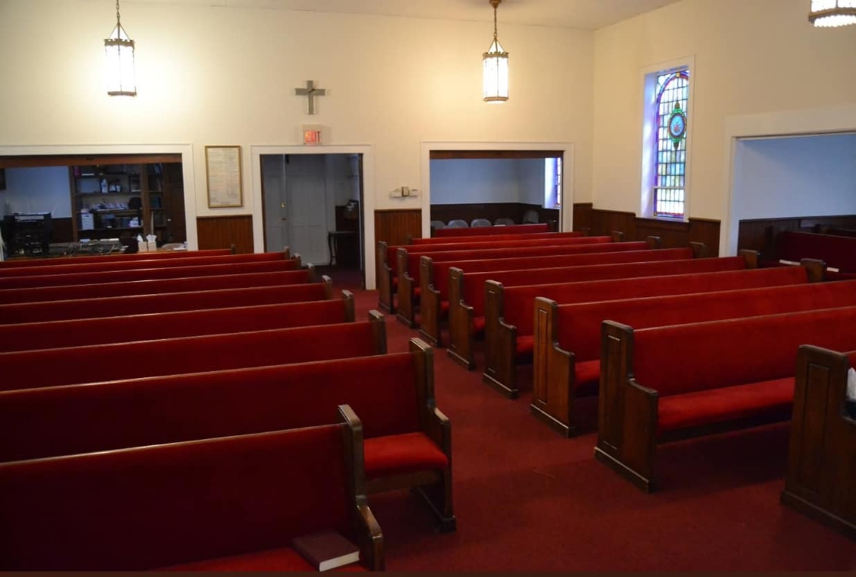 Sanctuary Rear and Entrance View (Before Renovation, 2013) Sanctuary interior of Rawls Baptist Church before 2013 remodel, showing cross above rear doors and red pew seating across the main floor.