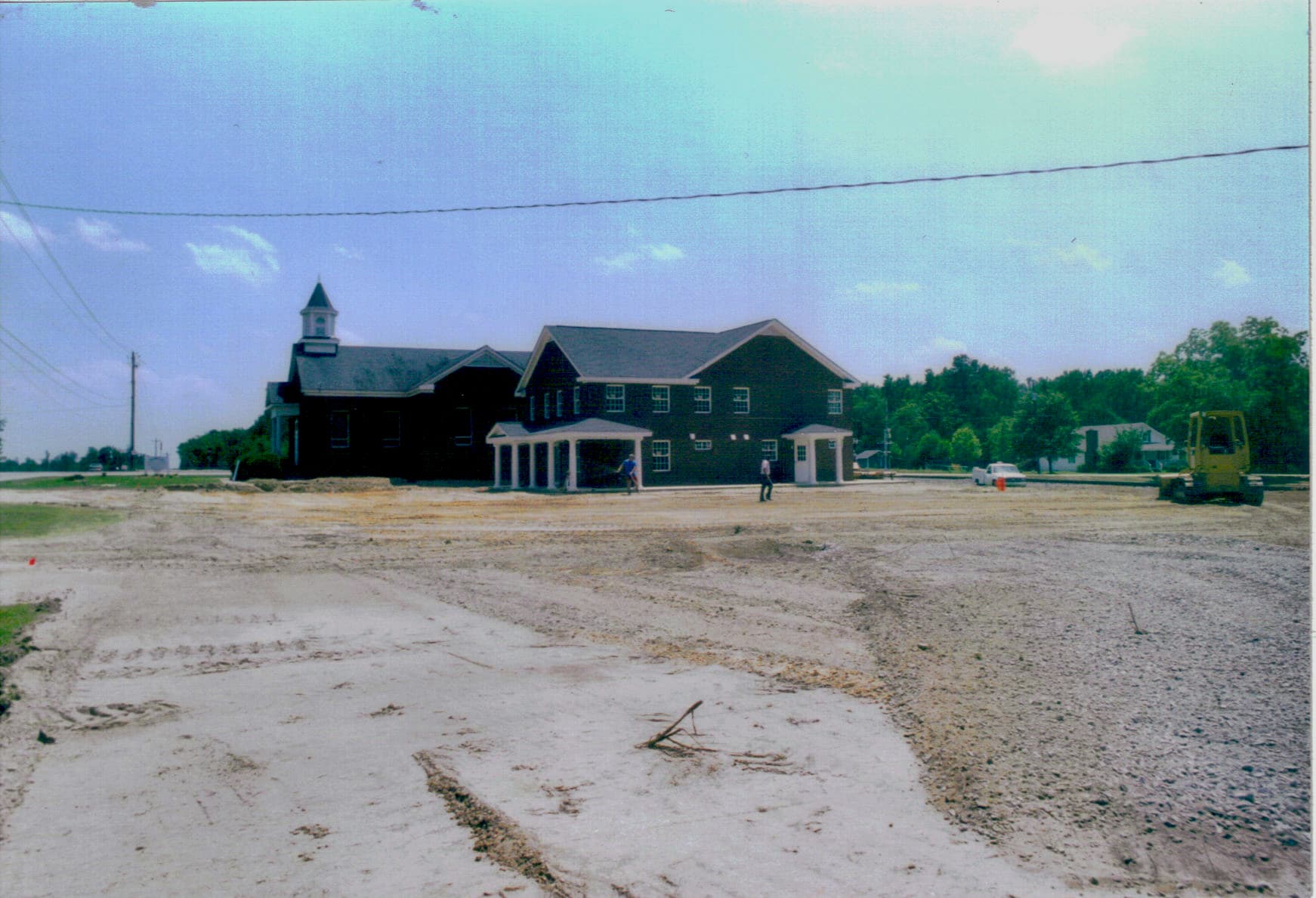 Nearly Finished, 2005 Exterior of Rawls Baptist Church in 2005 nearing completion after major expansion, showing new fellowship hall addition, finished brickwork, and open parking area under bright summer sky.