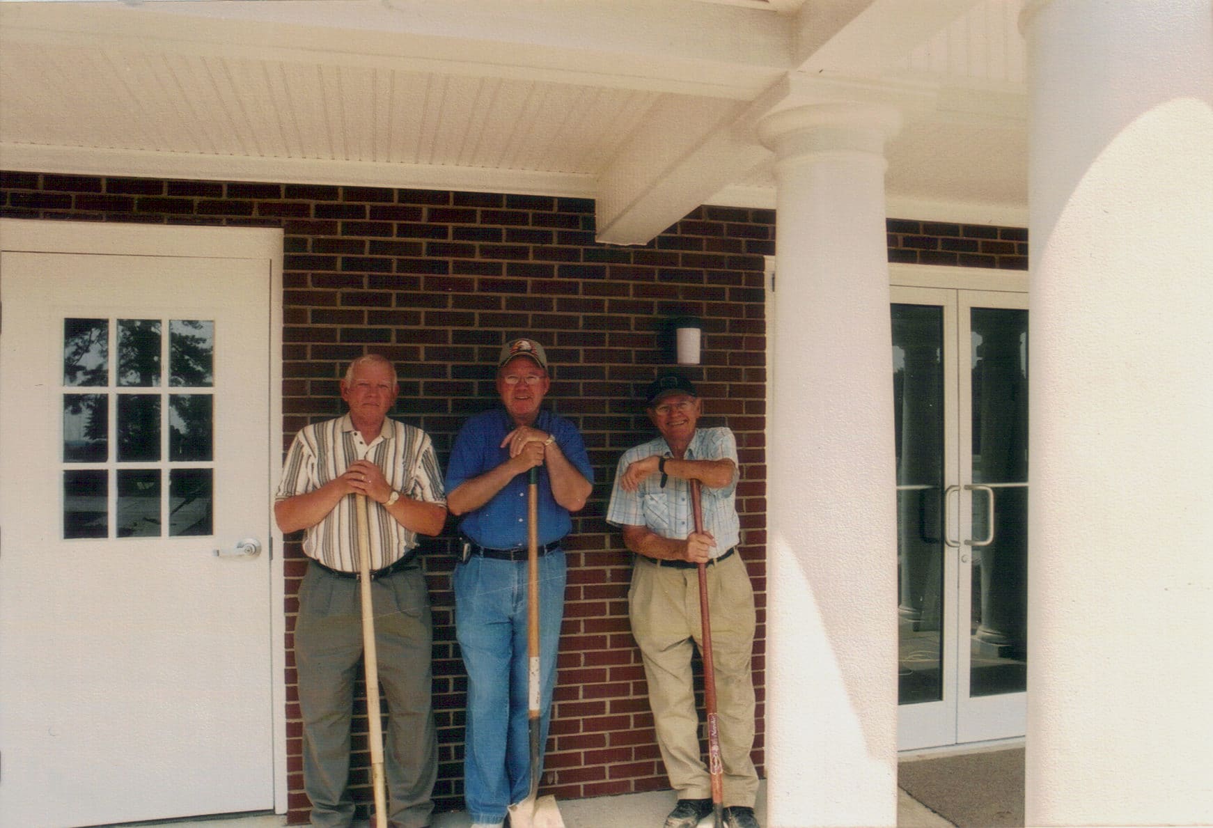 Finishing Touches on the Entrance, 2005 Three members of Rawls Baptist Church standing by the completed addition in 2005, marking the end of construction efforts.