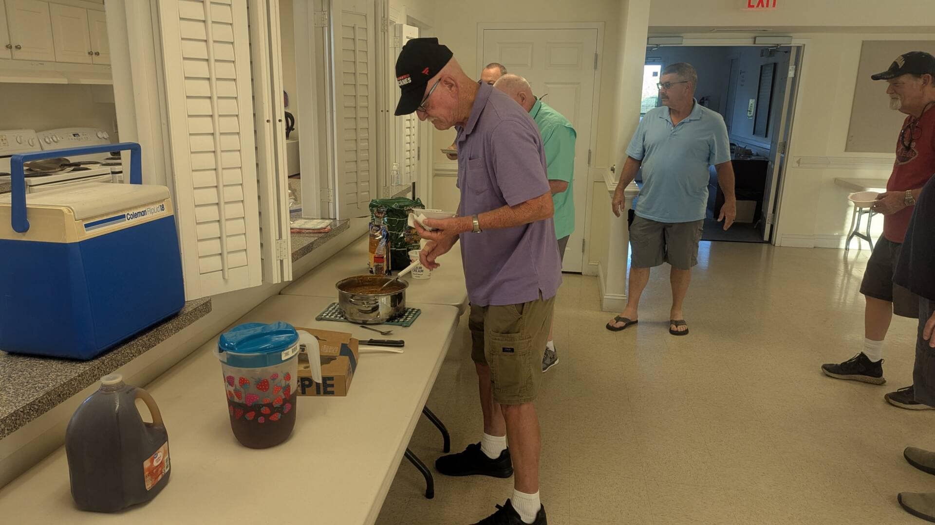 Men waiting in line and talking while getting food in Fellowship Hall of Rawls Baptist Church