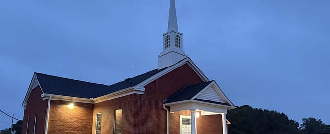 Rawls Baptist Church in Evening just before sunset with church lights glowing faintly. 