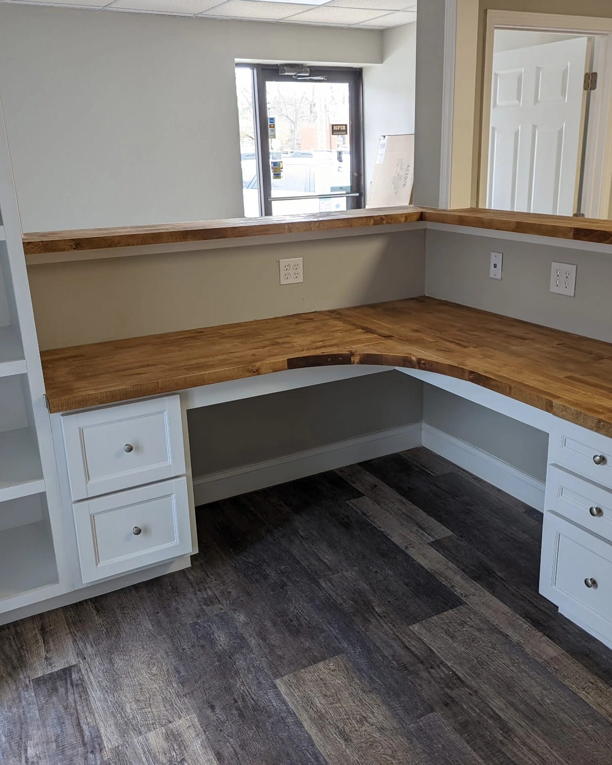 Custom L-shaped reception counter build featuring butcher-block tops and white built-in cabinetry.