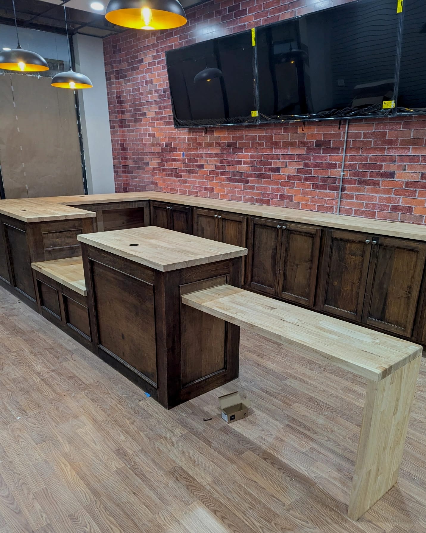 Custom wood counter installation inside a Sign & Copy store, featuring built-in cabinetry, multiple work surfaces, and mounted display TVs.