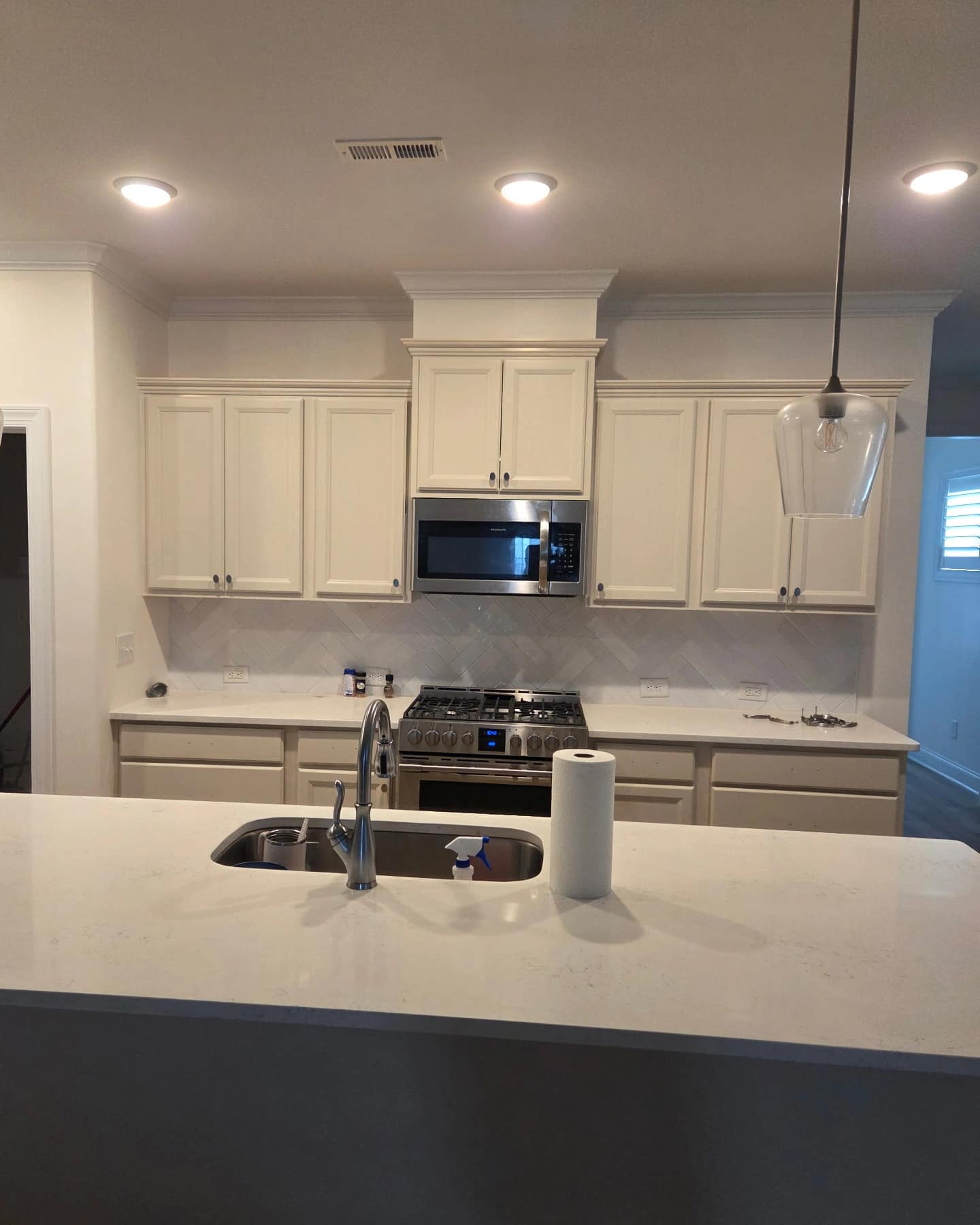 Deep blue shaker kitchen with quartz countertops, subway tile backsplash, and stainless appliances.