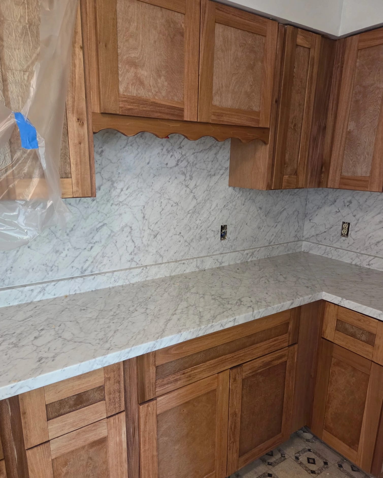 Natural wood kitchen with full marble-look backsplash and countertop installation.