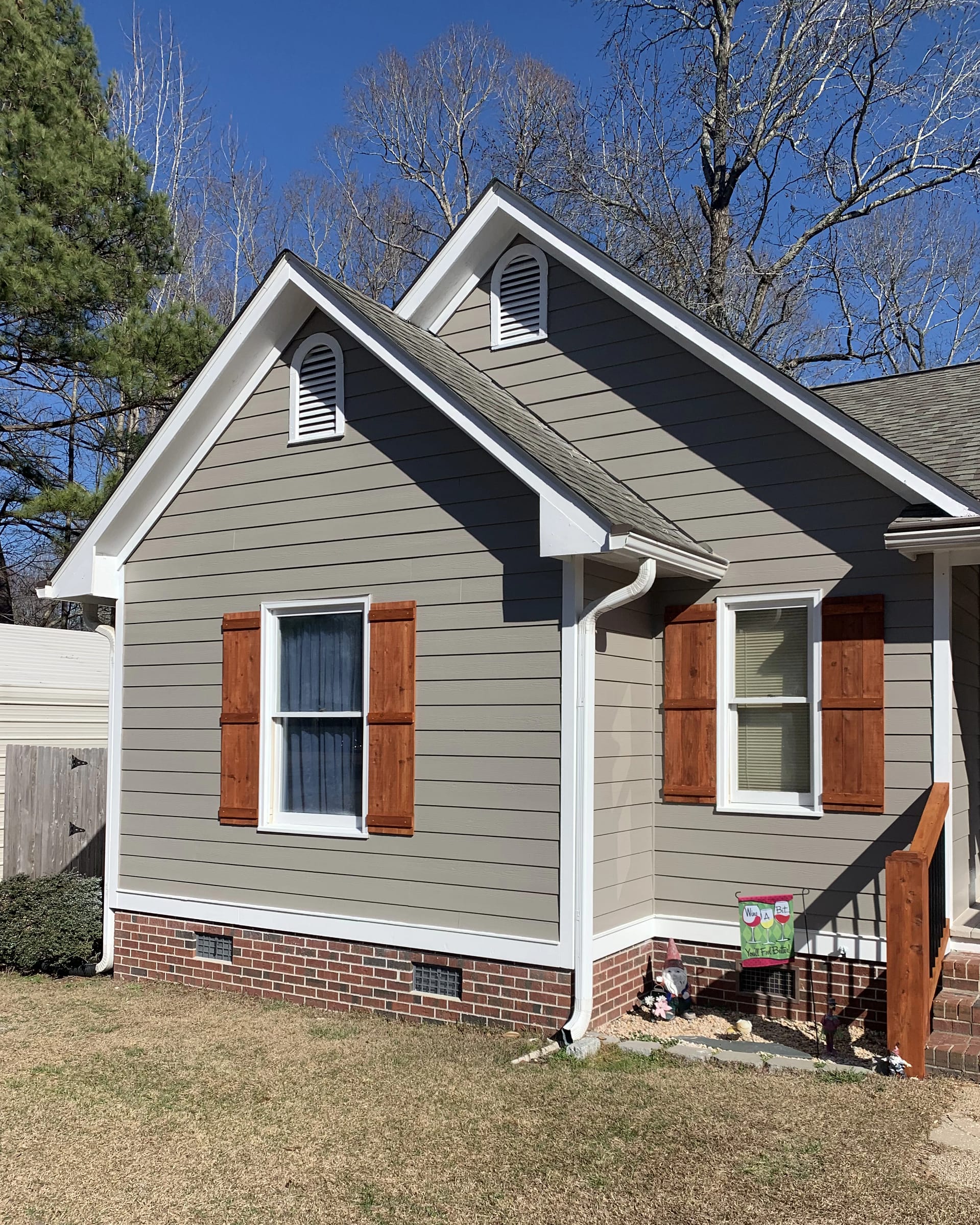 Light-gray Hardie siding with white trim and cedar shutters under dual front gables.