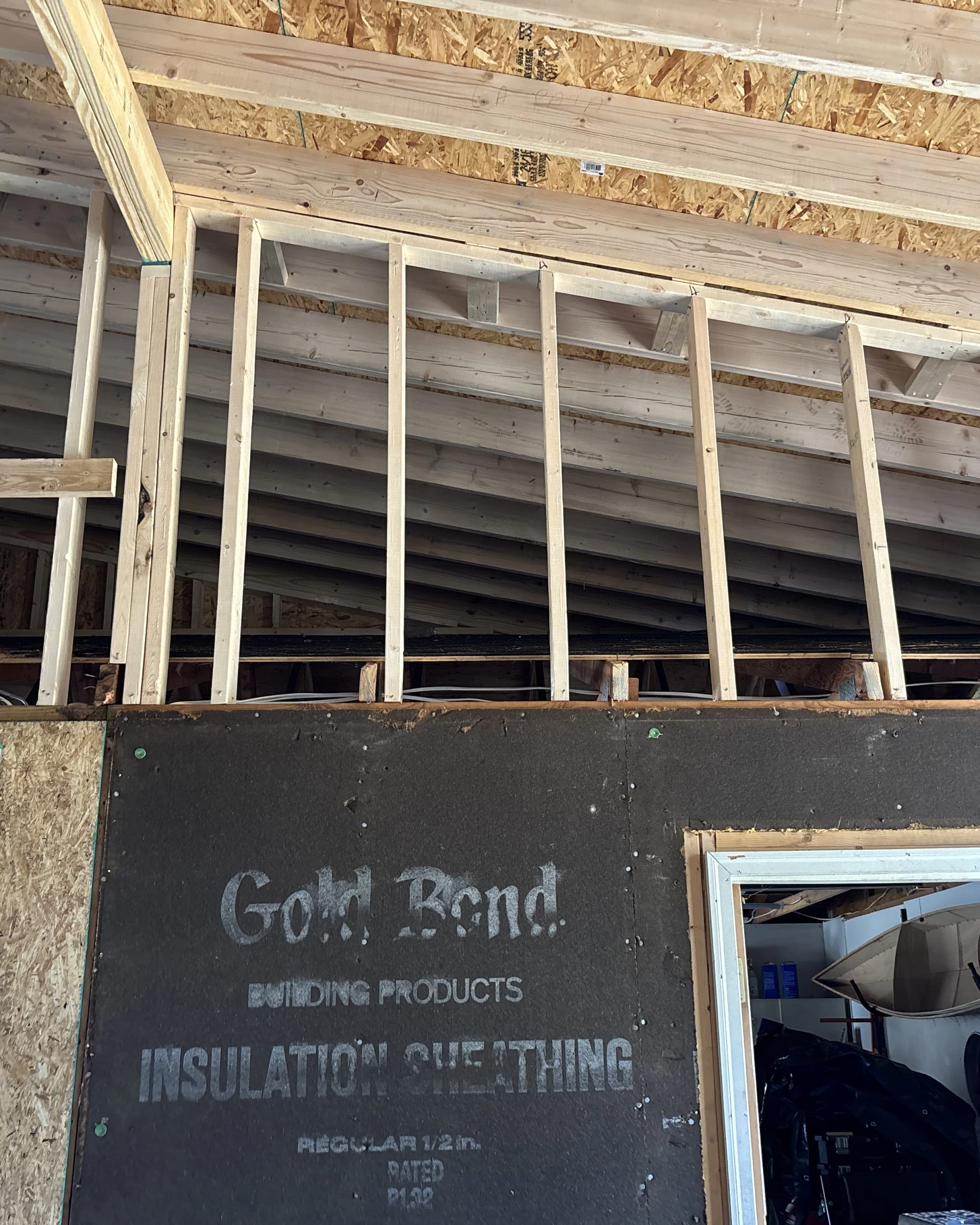 Garage remodel with sheathing installed and new framing visible around the ceiling area.