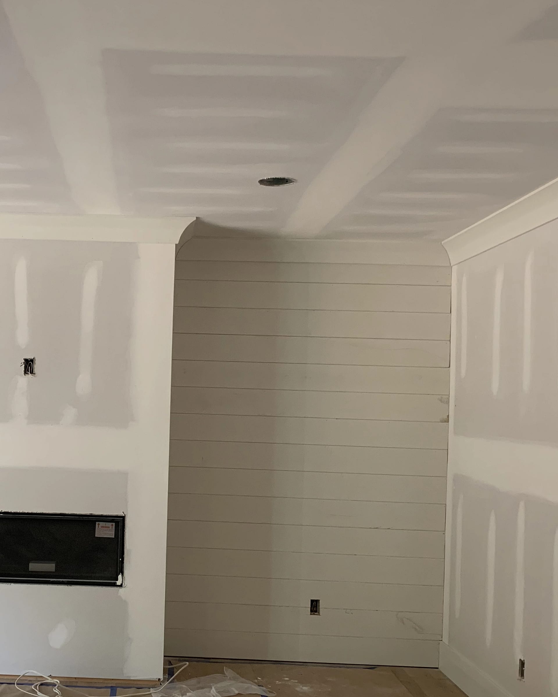 Shiplap accent wall being installed next to a newly framed fireplace area.