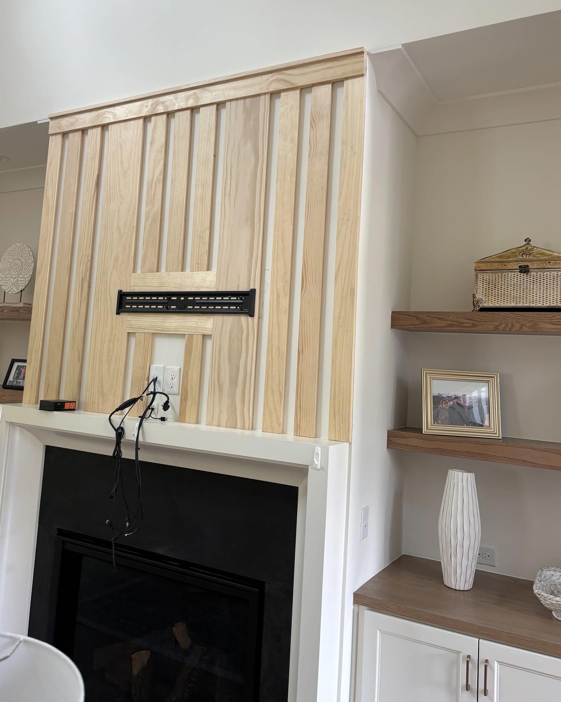 Wood slat-panel accent wall installation around fireplace with TV mount bracket.