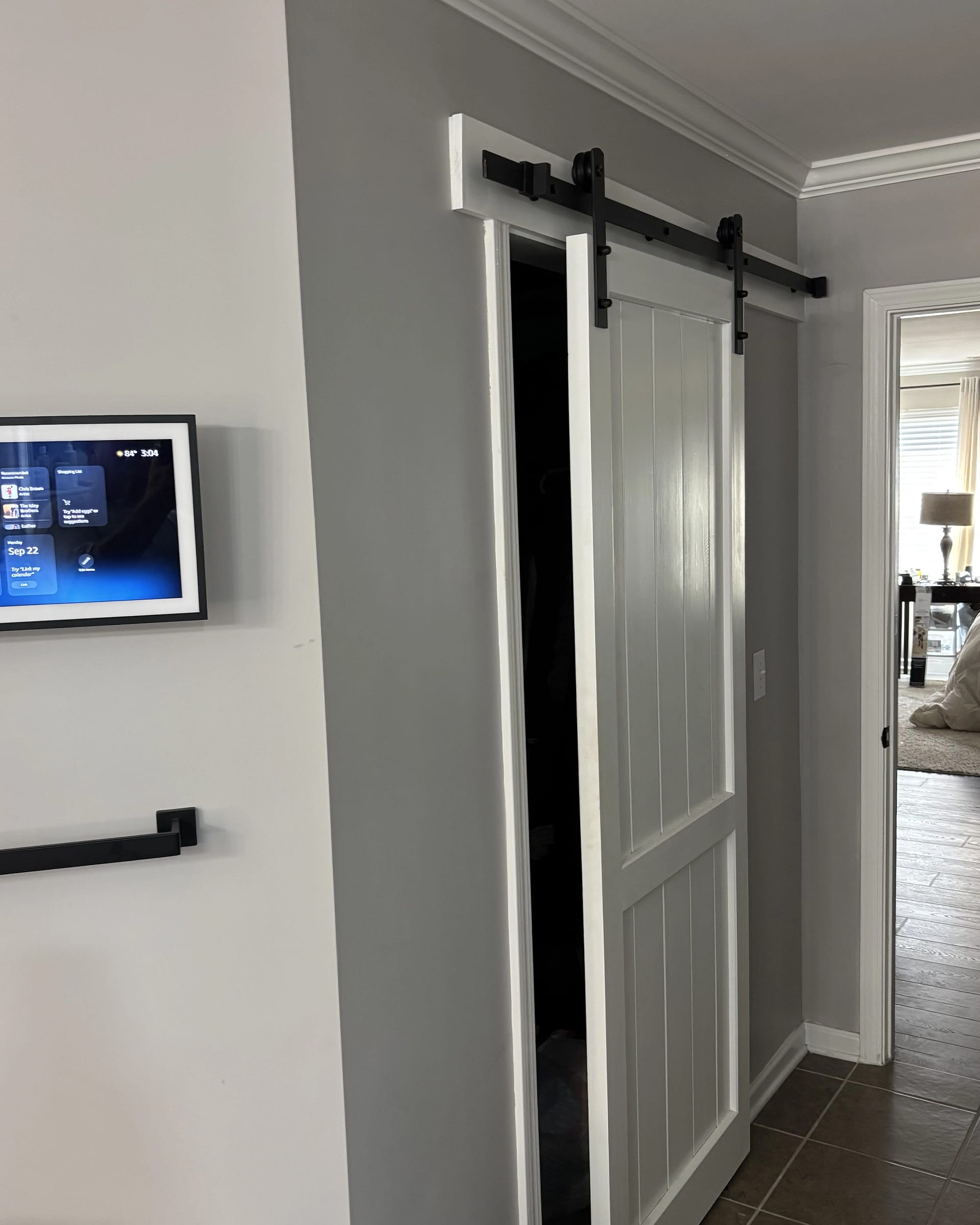 White barn door with black hardware and upgraded header trim detail.