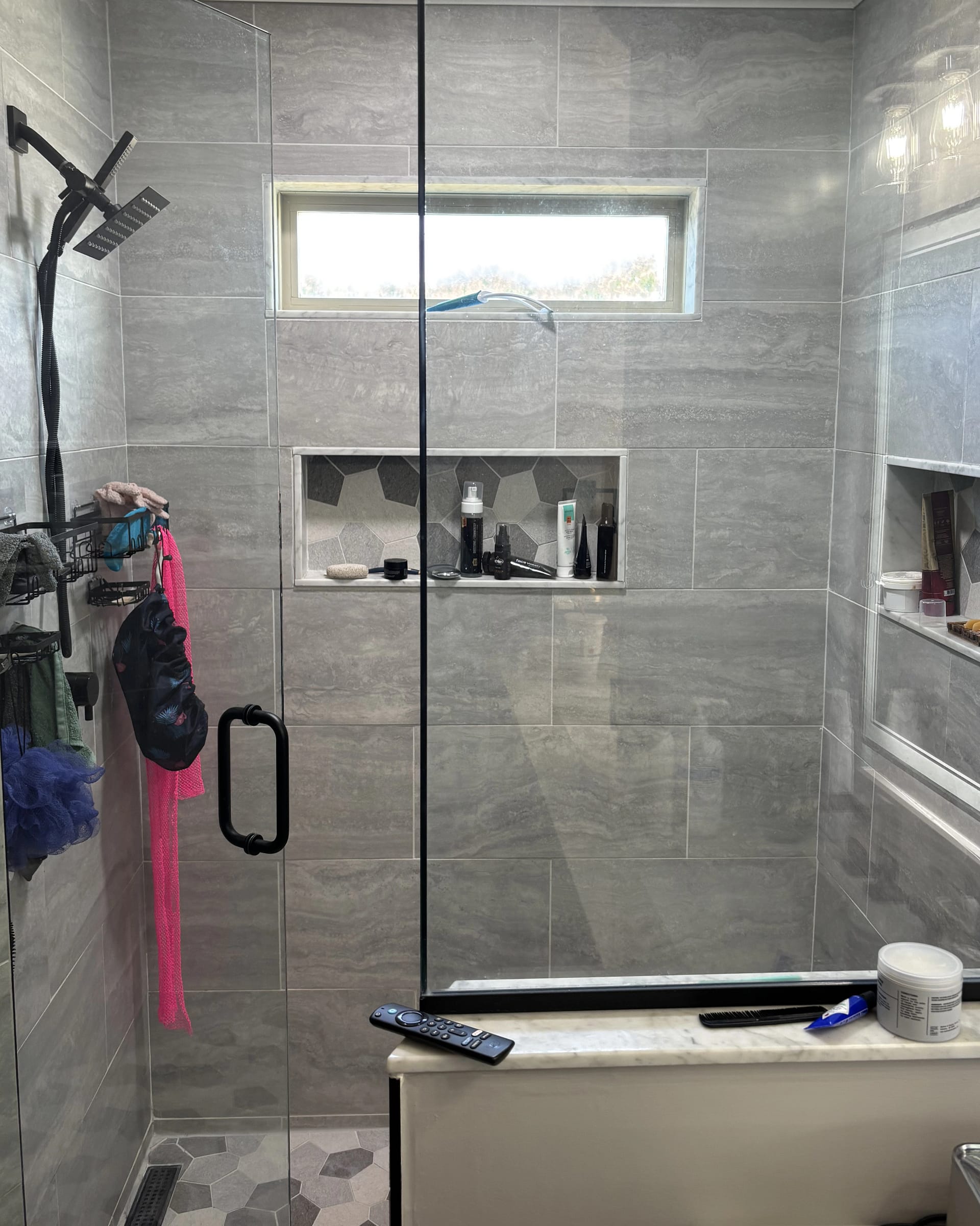 Gray tile walk-in shower featuring a horizontal window and geometric-tile recessed niche.