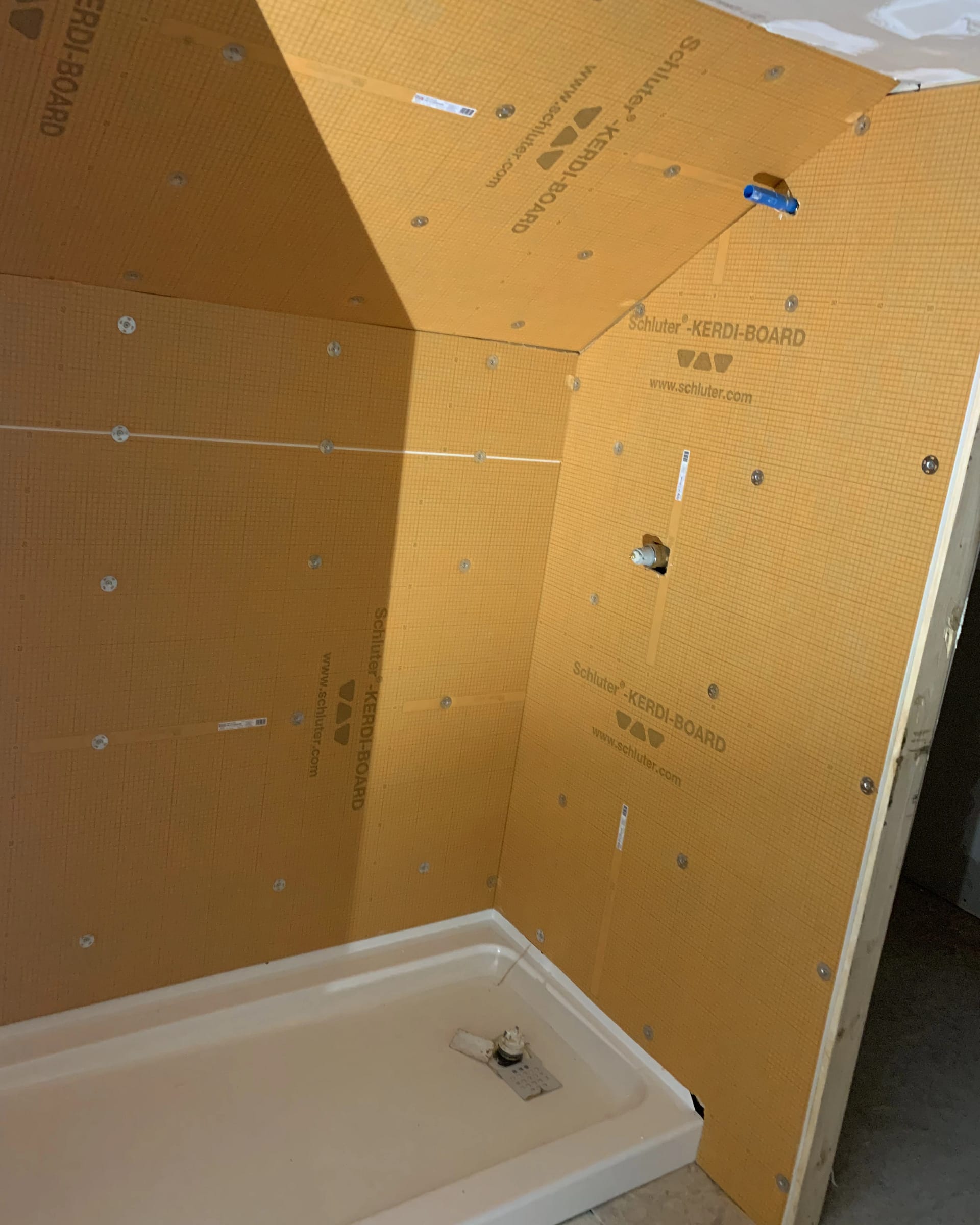 Walk-in shower under construction with Schluter Kerdi-Board waterproofing installed on walls.