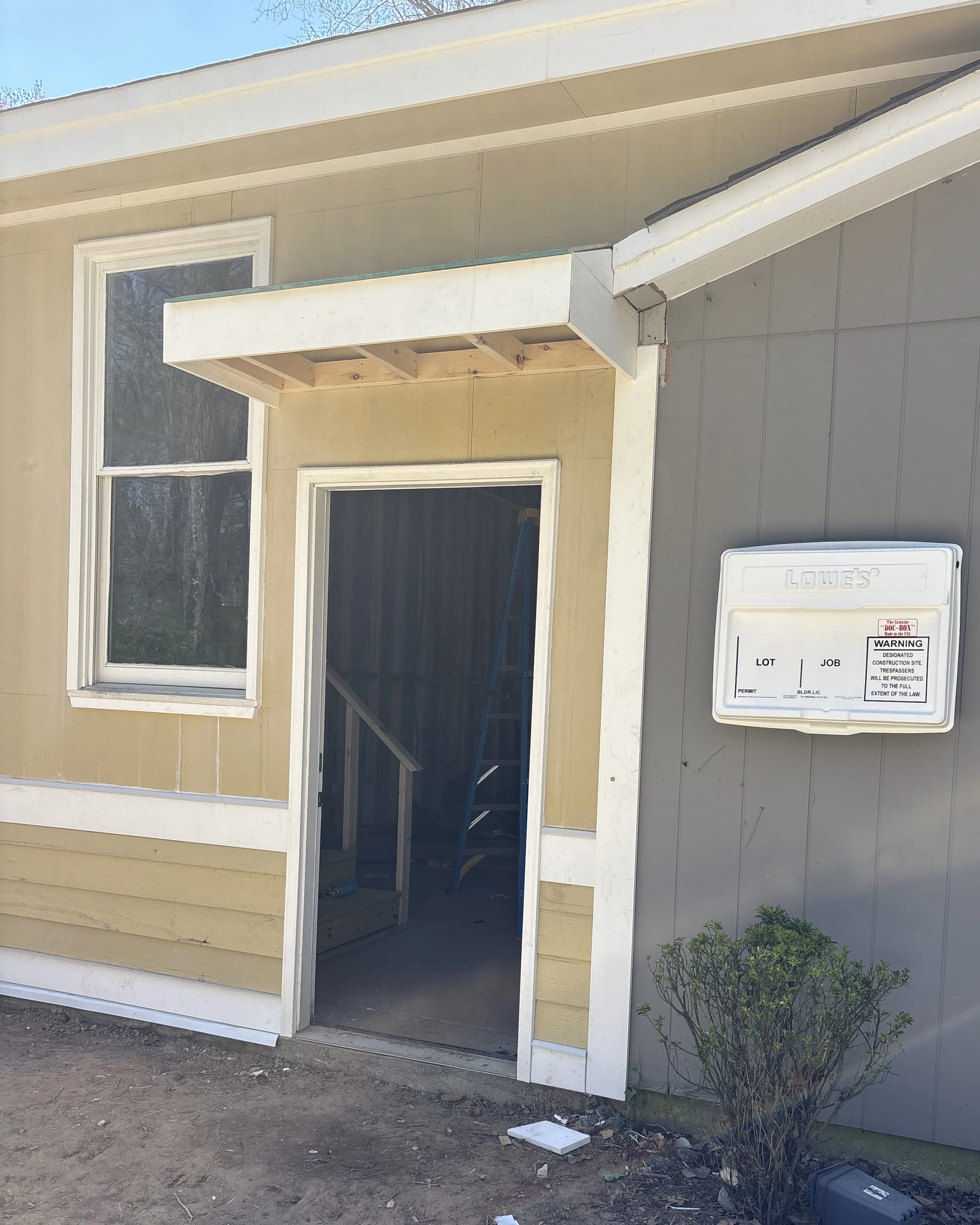 Framing for a small exterior entry awning being built above a side door.