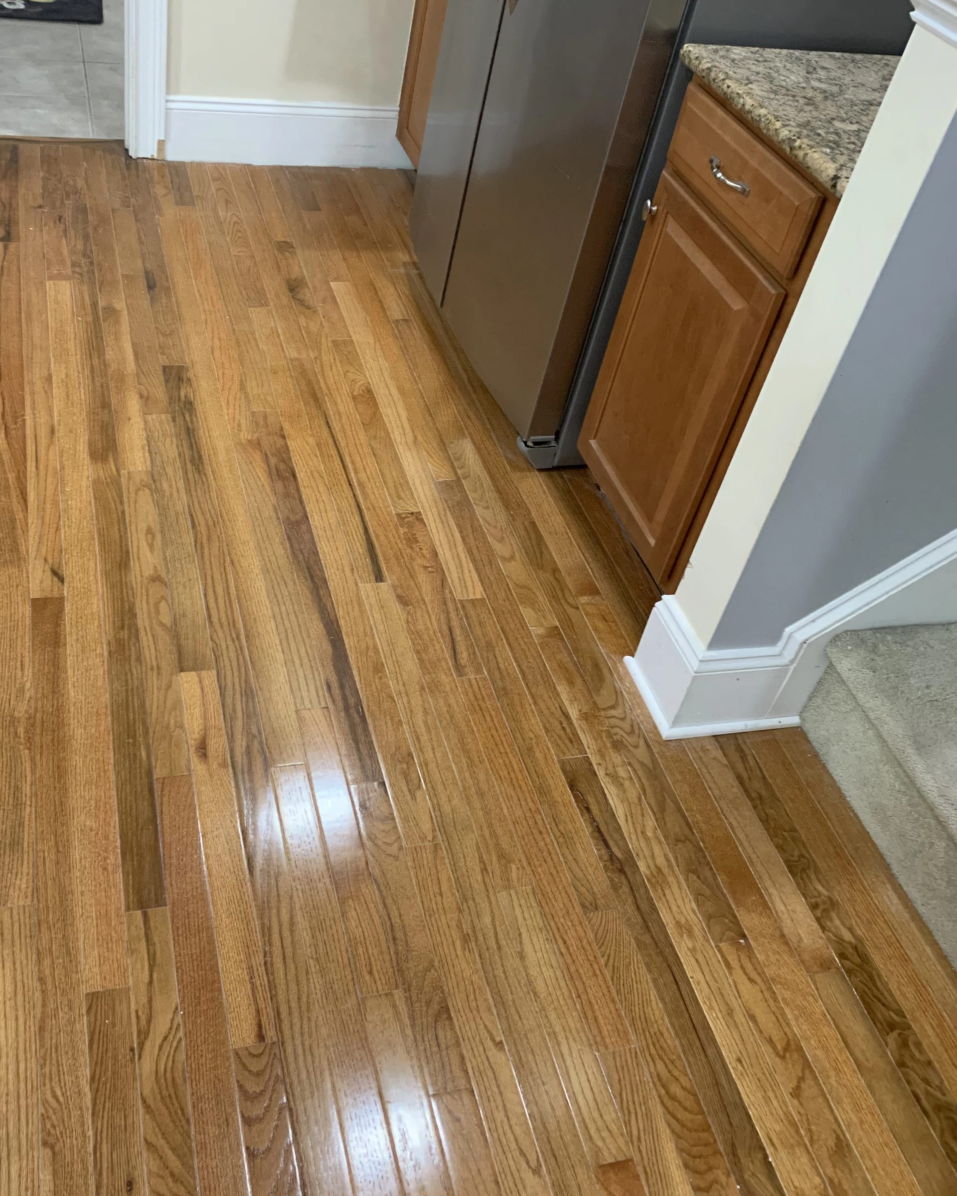 Refinished hardwood floors in a kitchen area with smooth, glossy protective coating.