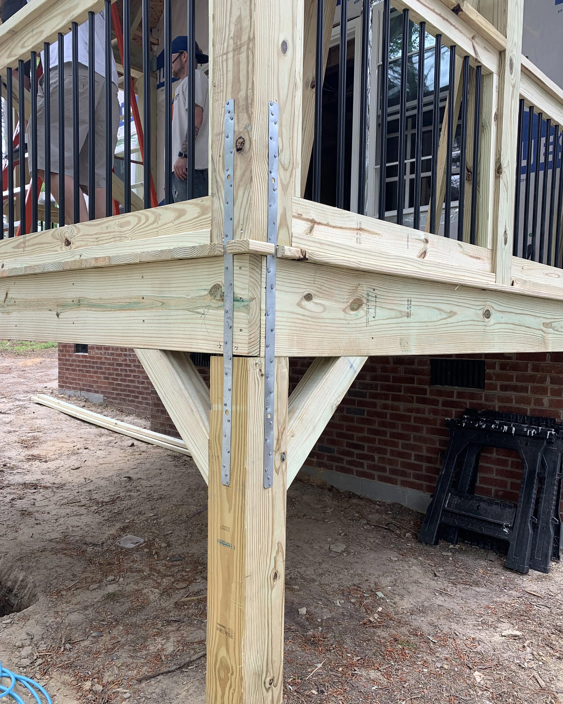 Corner post bracing with metal straps on a raised wood deck.