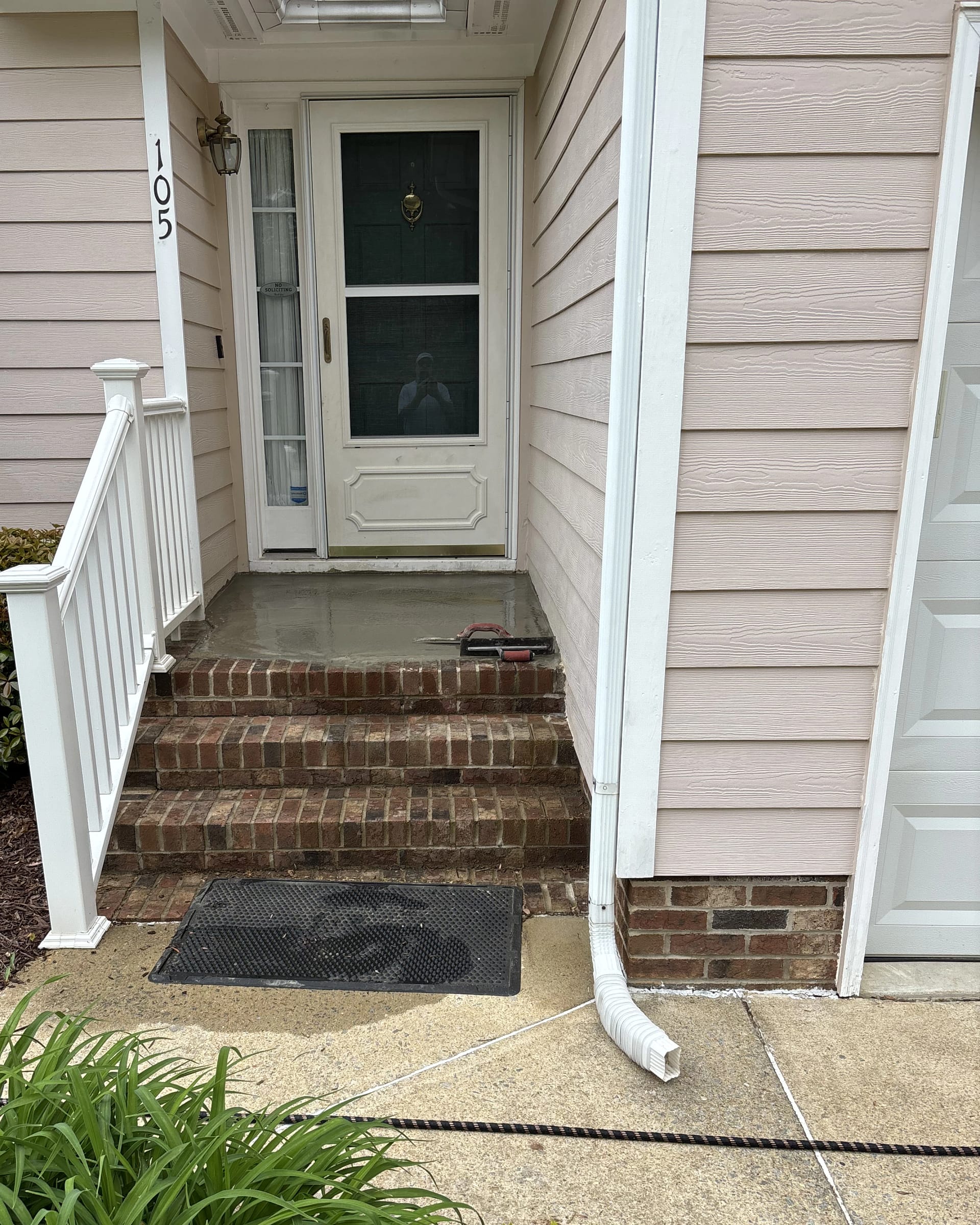 Front entry brick steps repaired with fresh concrete at the landing.