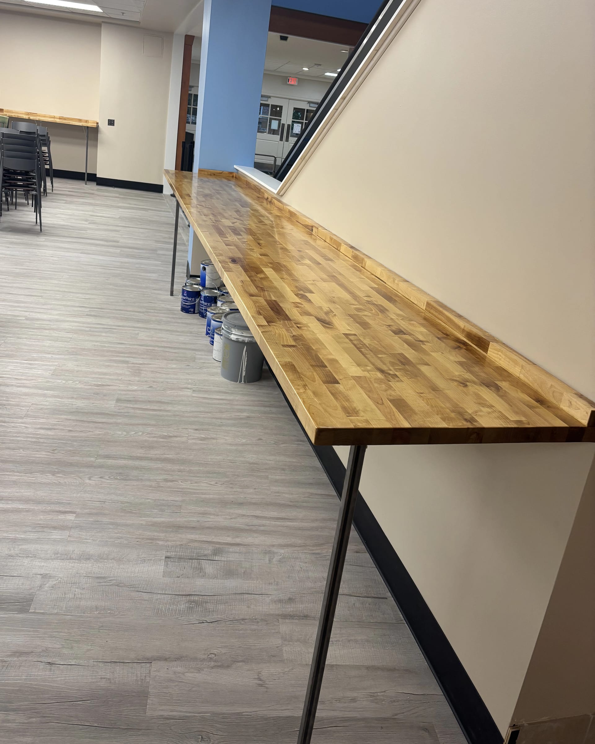 Long butcher block counter installed along a commercial or community space wall.