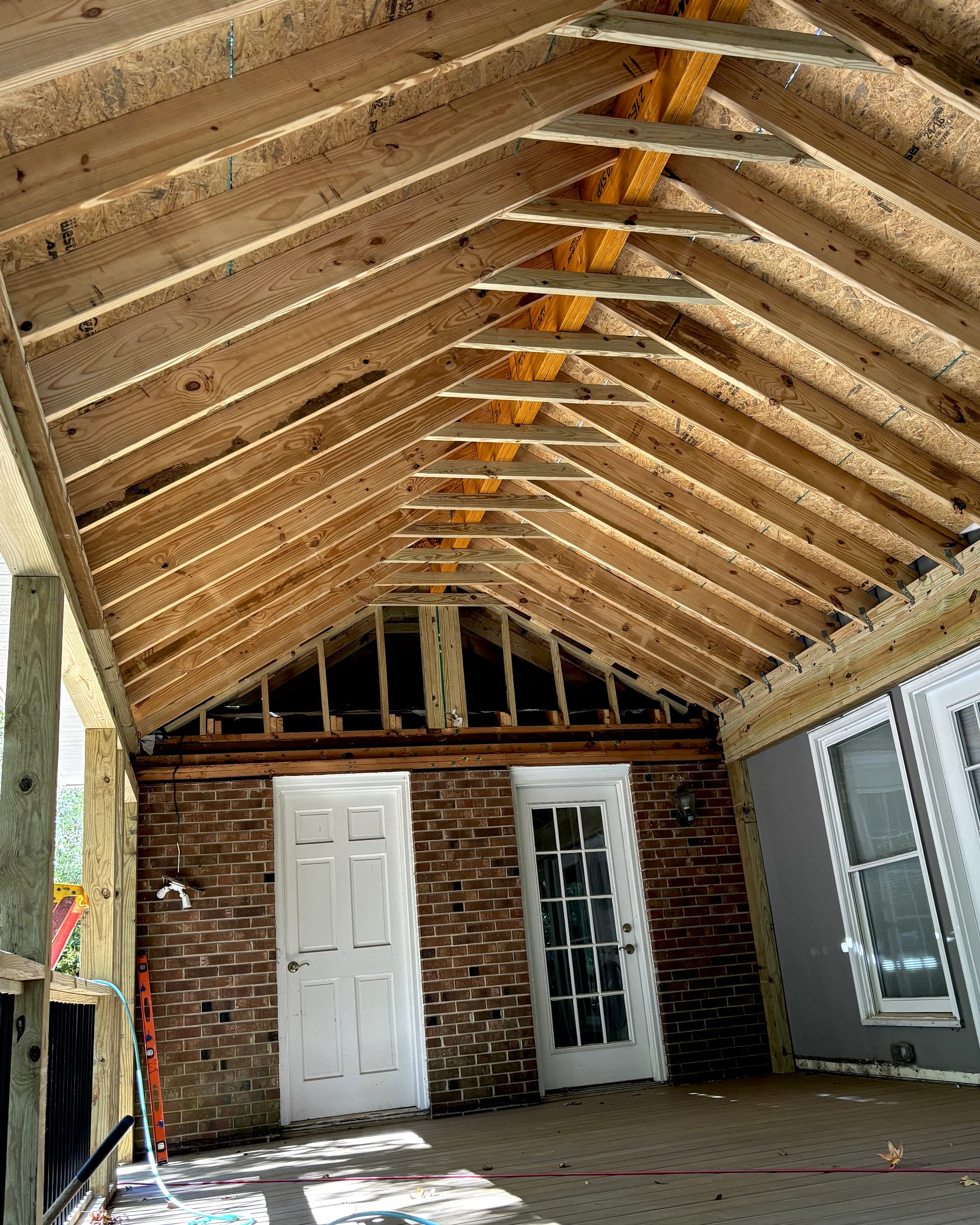 Vaulted ceiling framing with exposed rafters and structural supports over an enclosed porch remodel.
