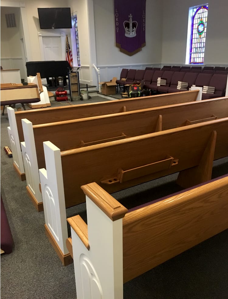 Sanctuary Seating Installation – Mid Progress (2018) Rows of newly installed pews at Rawls Baptist Church sanctuary in 2018, showing modern design, white end panels, and improved seating layout.
